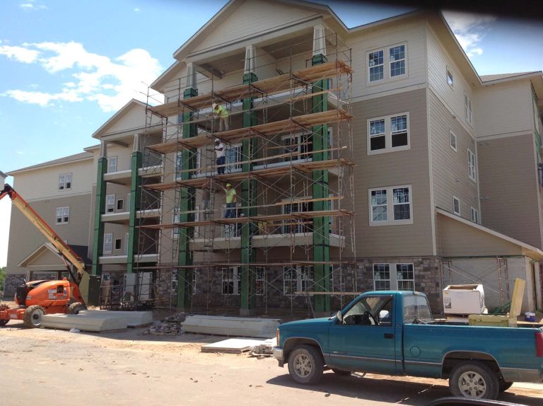 workers on scaffolding repair exterior siding and roof