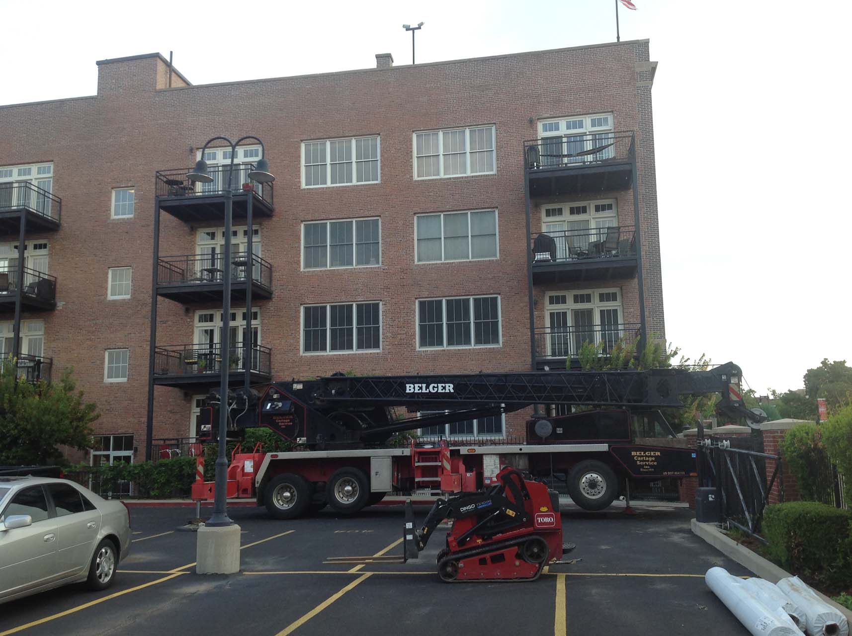 A crane truck is parked in front of a multi-unit apartment