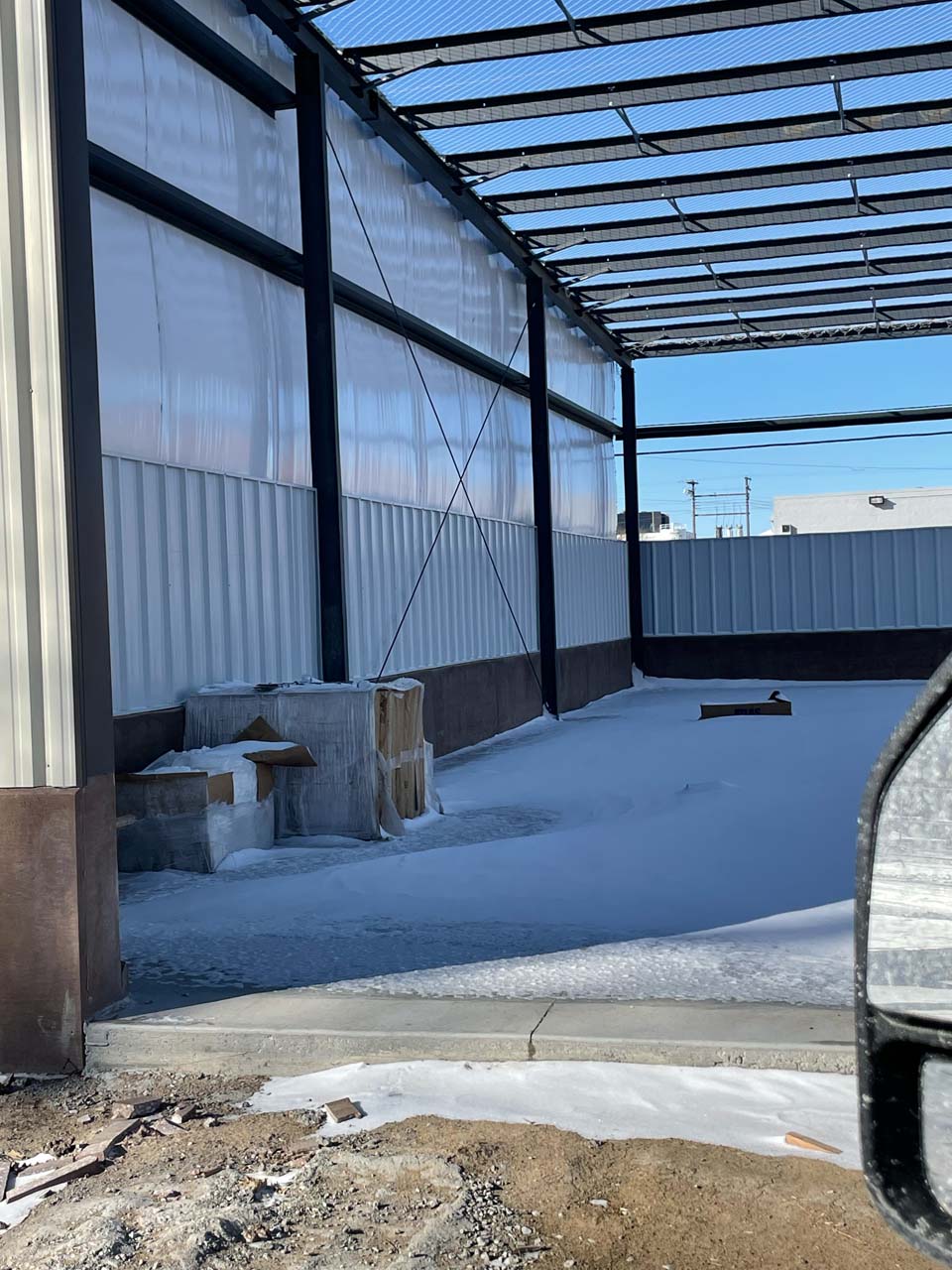A metal building doesn't have a roof yet and snow is inside