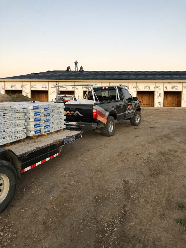 A New image truck pulls pallets of roofing materials to a site