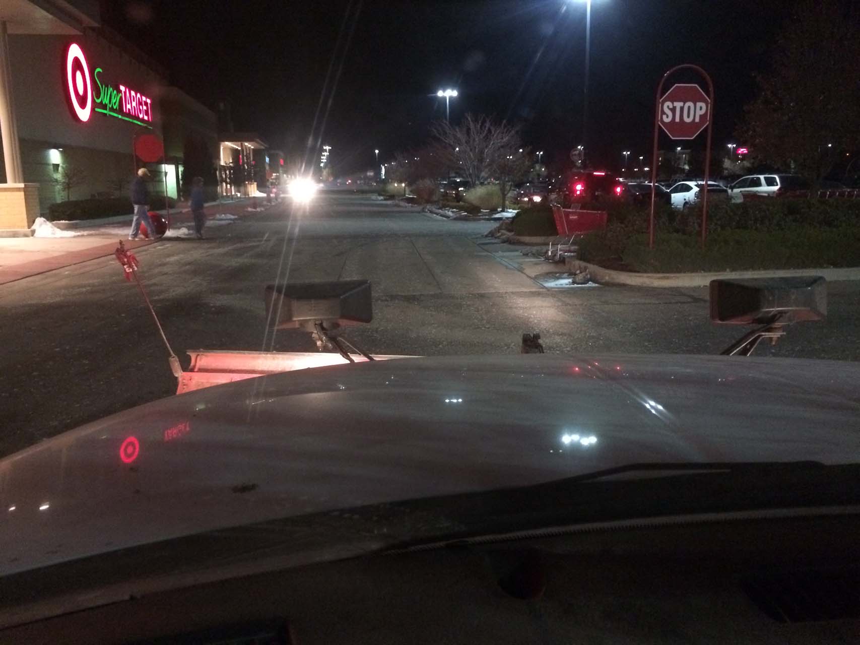 Snow removal vehicle drives down a parking lot at night